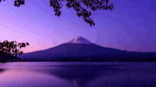 a lake with a mountain in the background and a purple sky