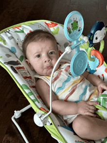 a baby laying in a bouncer with a toy attached to it