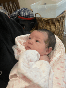 a baby is wrapped in a pink blanket and looking up at the camera