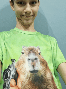 a young boy wearing a green shirt with a capybara holding a gun