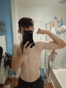 a shirtless man is taking a picture of his muscles in a bathroom