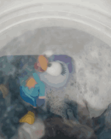 a toy penguin in a bucket of water with bubbles