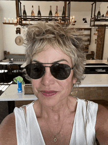 a woman wearing sunglasses takes a selfie in front of a bar