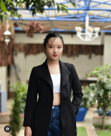 a woman wearing a black jacket and jeans stands in front of a blue roof