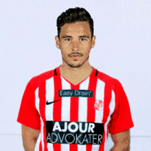 a man wearing a red and white striped shirt with ajour advokater on it