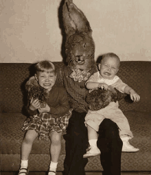 a man dressed as a bunny is sitting on a couch with two children