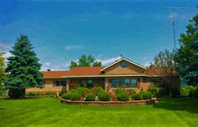 a brick house with a red roof has a round window on the front of it