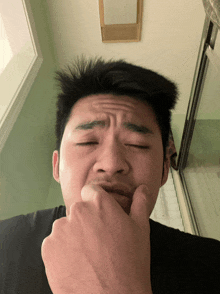 a man covering his mouth with his hand and making a face