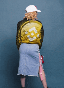 a woman wearing a denim skirt and a yellow jacket has a coin on her back