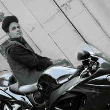 a man is sitting on a black motorcycle in front of a wall