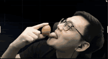 a man wearing glasses is eating an egg with his tongue sticking out