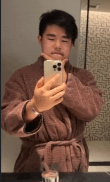 a man in a robe is taking a picture of himself in a mirror