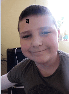 a boy with the letter a on his forehead smiles