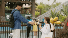 a man giving an ice cream cone to a woman in front of a sign that says ' a '