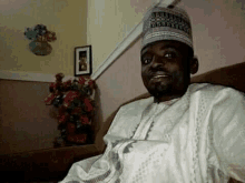 a man is sitting on a couch wearing a hat and a white shirt .