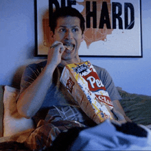 a man eating a bag of potato chips in front of a sign that says die hard