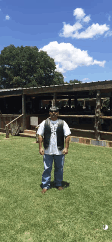 a man wearing a vest that says ' texas ' on it stands in a grassy field