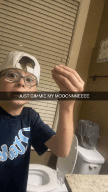 a boy wearing glasses and a hat is holding something in front of a toilet with the caption just gimmie my moonnneeee