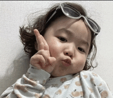 a baby wearing sunglasses and making a peace sign