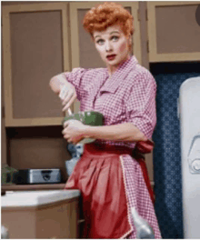 a woman in an apron is washing dishes in the kitchen