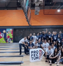 a group of people are posing for a photo in a bowling alley with a sign that says pro fec tum