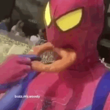 a person wearing a pink spiderman costume is eating a donut .