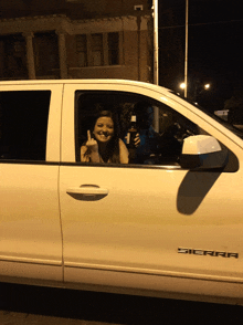 a woman giving a thumbs up while sitting in a white sierra truck