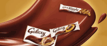 three galaxy candy bars are sitting on a brown surface