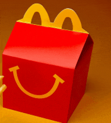 a red mcdonald 's happy meal box with a yellow smiley face