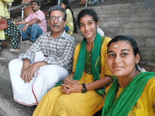 a man in a plaid shirt sits next to two women