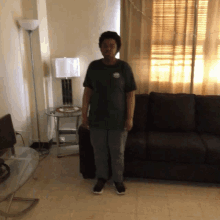 a man in a green shirt stands in front of a couch in a living room