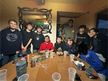 a group of young boys are gathered around a table with a bottle of sunkist on it