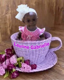 a baby in a purple wicker cup with the name laurine gabrielle written on it