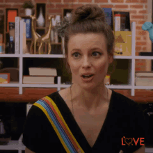 a woman with a bun on her head is standing in front of a bookshelf with books on it .