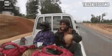 a man and a woman are sitting in the back of a truck with trash italiano written on the bottom .