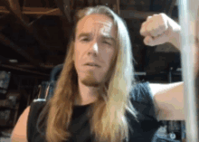 a man with long blonde hair and a beard is flexing his arm