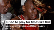 a man in a chicago bulls jersey is crying while holding a trophy while another man looks on .