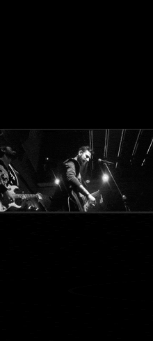 a man is playing a guitar and singing into a microphone on a stage in a black and white photo .