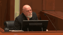 a man sits at a desk in front of a computer with a law and crime sign on the desk