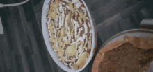 a casserole dish filled with vegetables and cheese sits on a wooden table