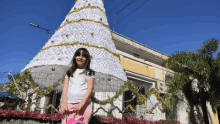 a little girl is standing in front of a christmas tree