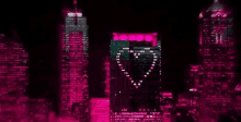 a city skyline at night with a pink heart shaped light on a building .