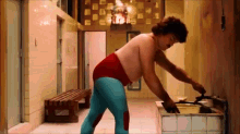 a shirtless man in blue and red tights is standing in a hallway