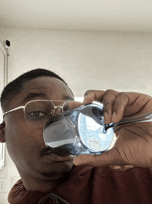 a man wearing glasses is holding a glass in front of his mouth