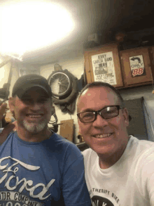 two men are posing for a picture with one wearing a ford t-shirt