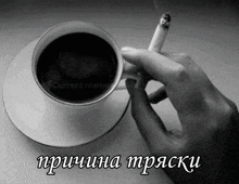 a person holding a cigarette next to a cup of coffee that says current meme