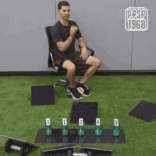 a man is sitting in a chair in a gym next to a table with a row of cups on it .