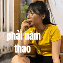 a woman wearing glasses and a yellow shirt has the word thao on the bottom