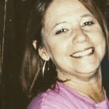 a close up of a woman wearing a pink shirt and smiling .