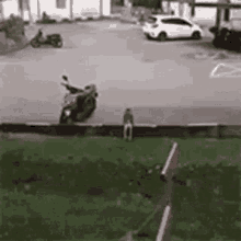 a man is riding a motorcycle in a parking lot while another man sits on a bench .